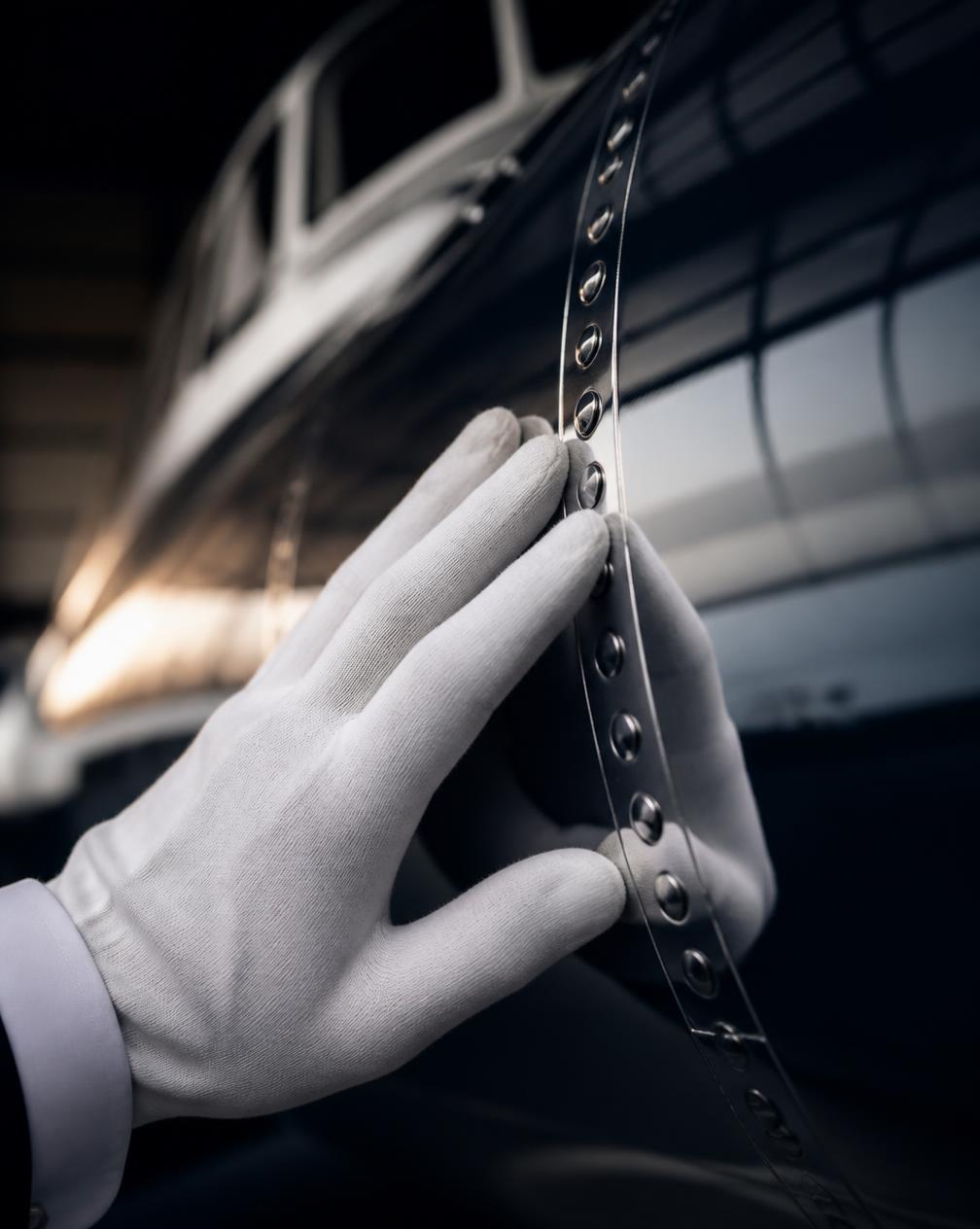 Gloved hand inspecting a polished rivet line on a fuselage